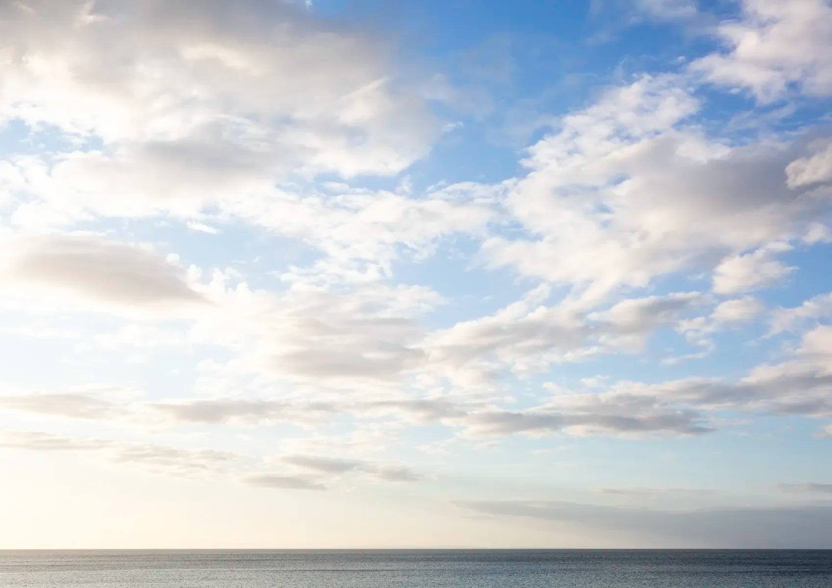 Blue sky with scattered clouds over a body of water