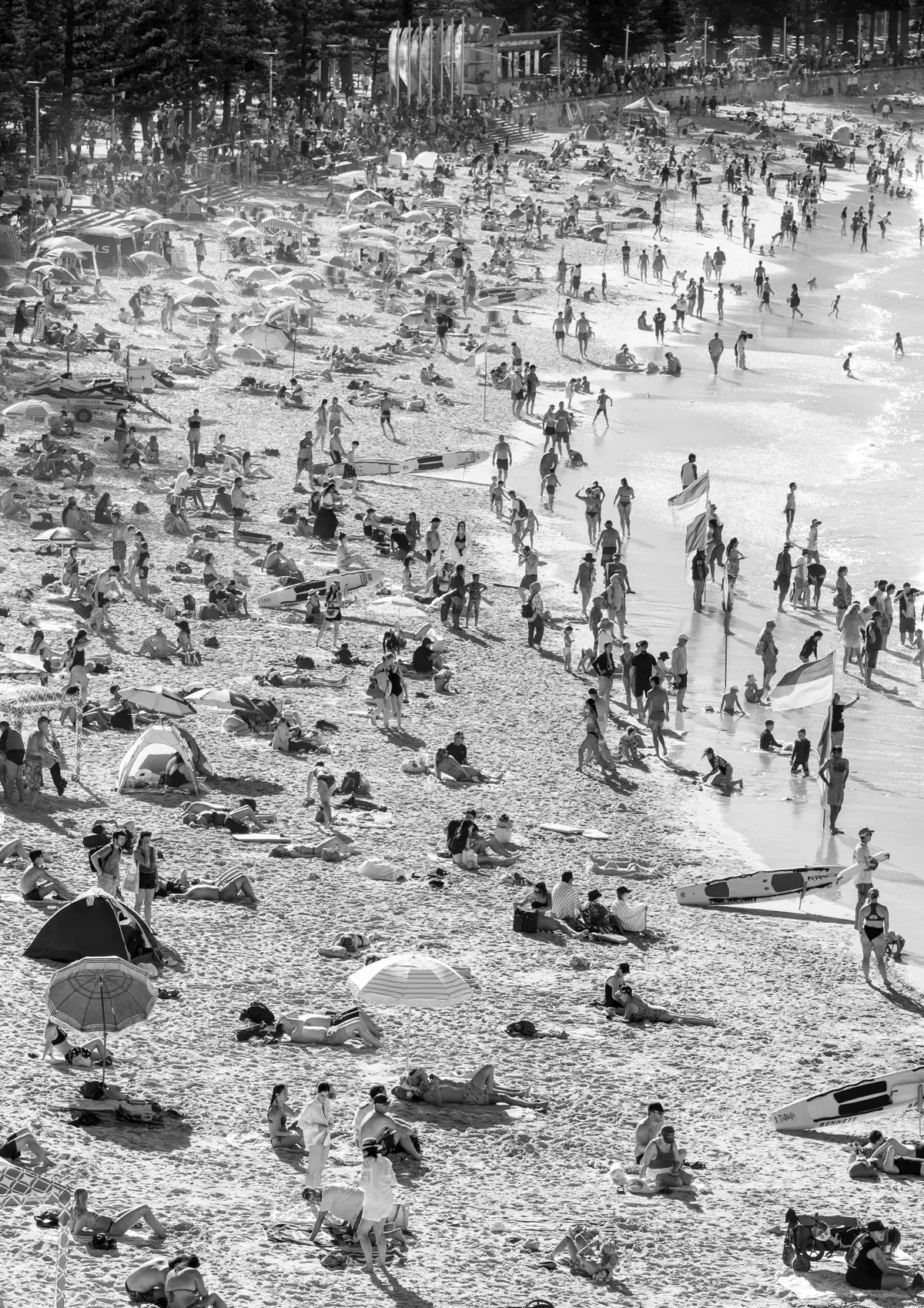 Black and white photo of a crowded beach with people and umbrellas.