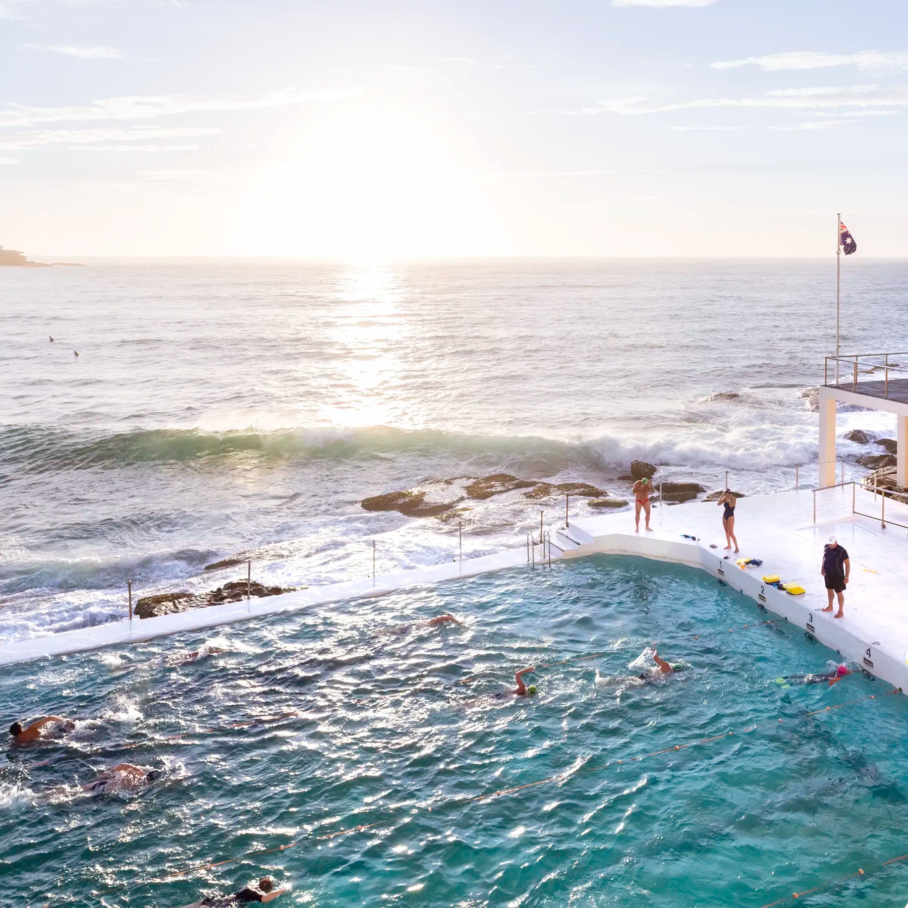 People swimming in an ocean pool with a view of the sea and sky.