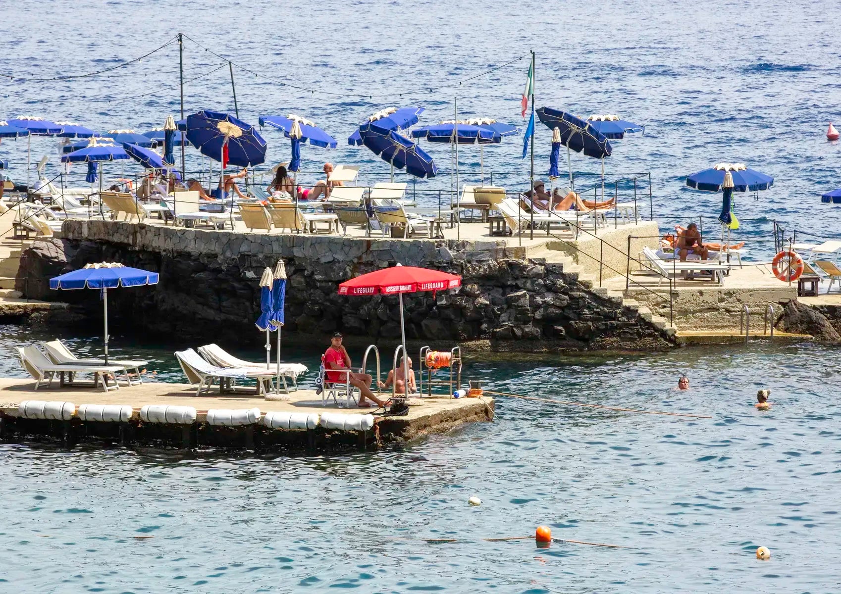 Rocky platform with lounge chairs and sun umbrellas next to the ocean