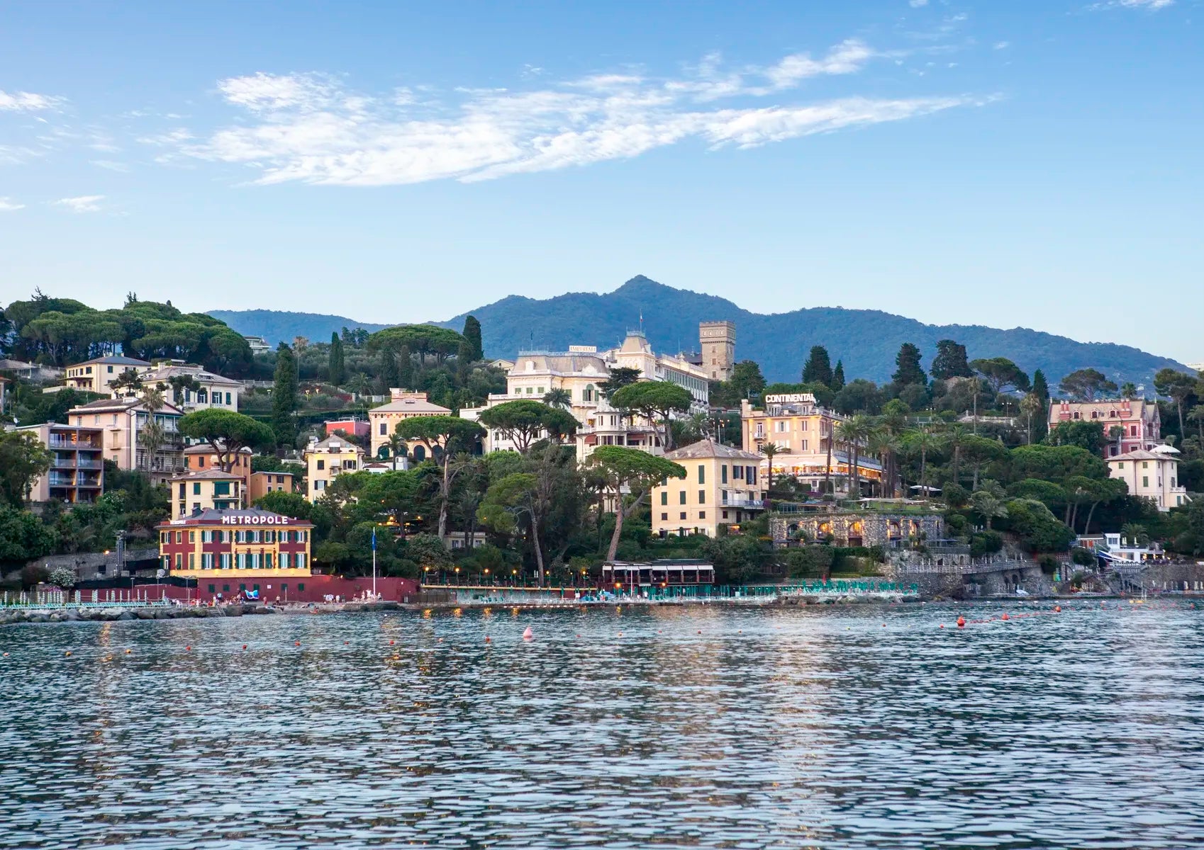 Cityscape with buildings along a waterfront, mountains in the background