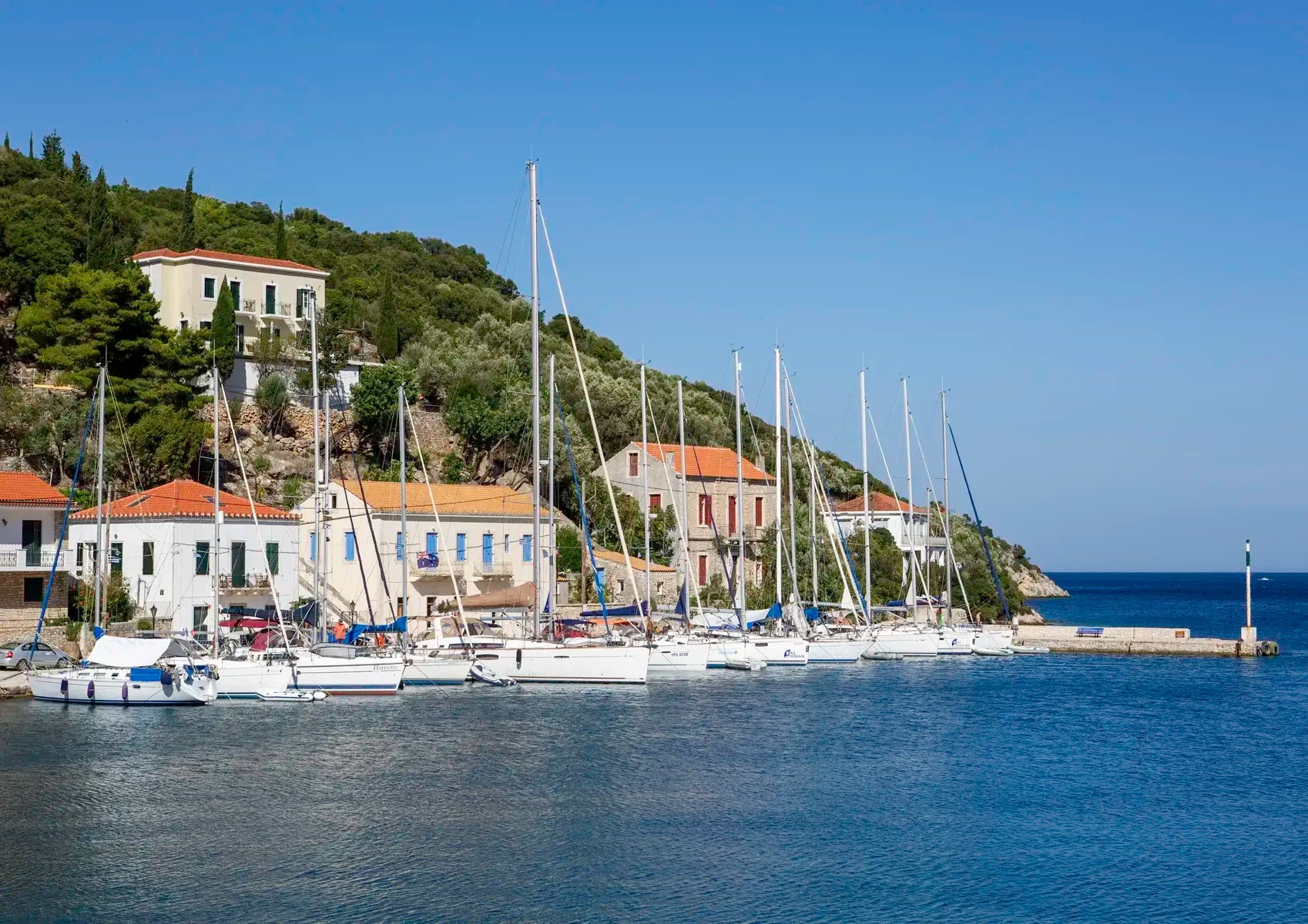 Kioni harbour with sailboats and buildings on a hillside under a clear blue sky.