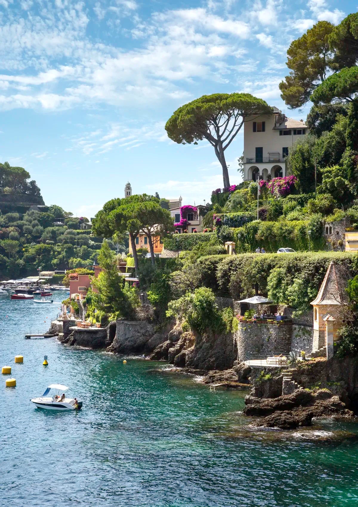 Coastal scene with houses, trees, and a boat on a clear day in Portofino.