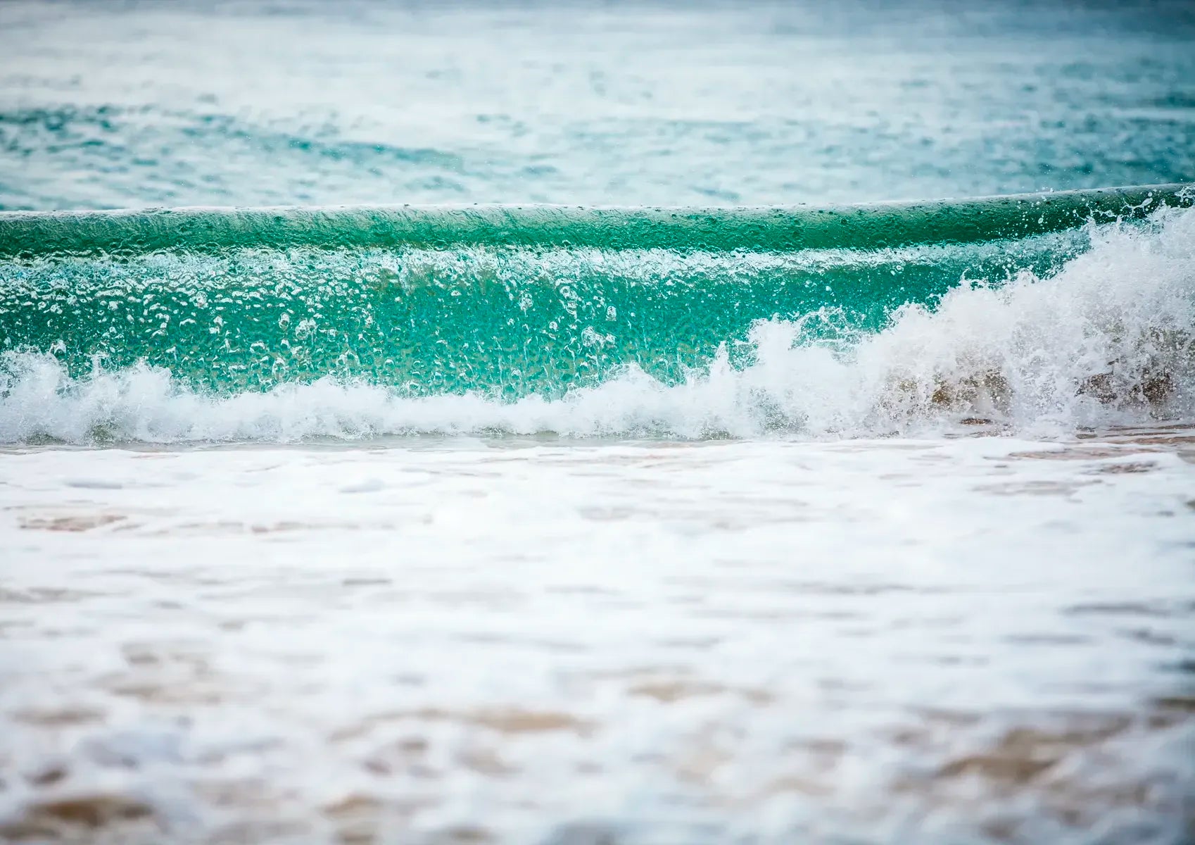 Wave crashing onto a beach with a clear sky