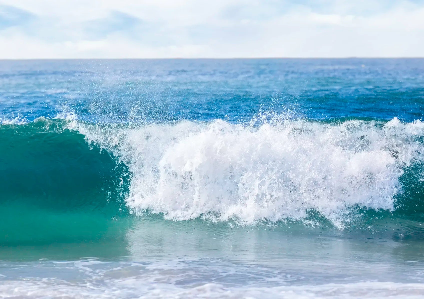 Wave crashing on a beach with a clear sky