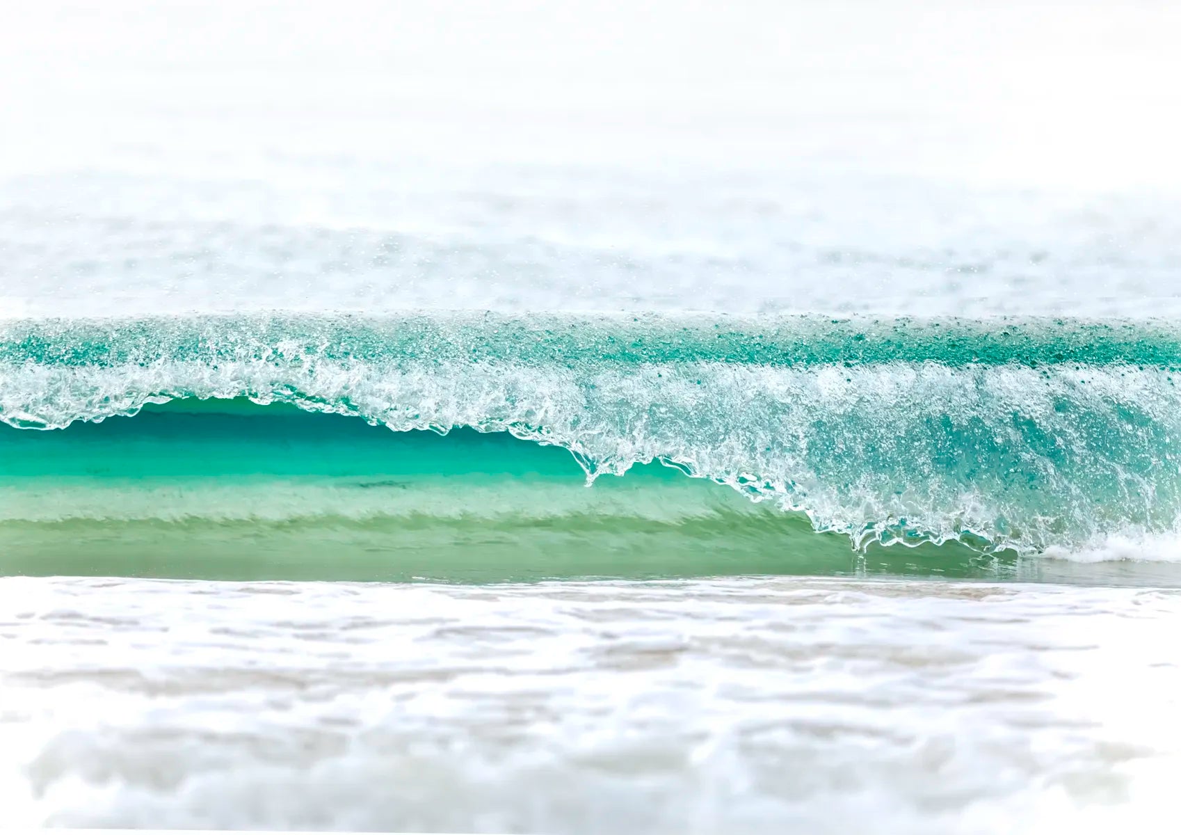 Close-up of a wave with white foam on a beach