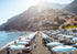Beach scene with umbrellas, people, and a mountainous background