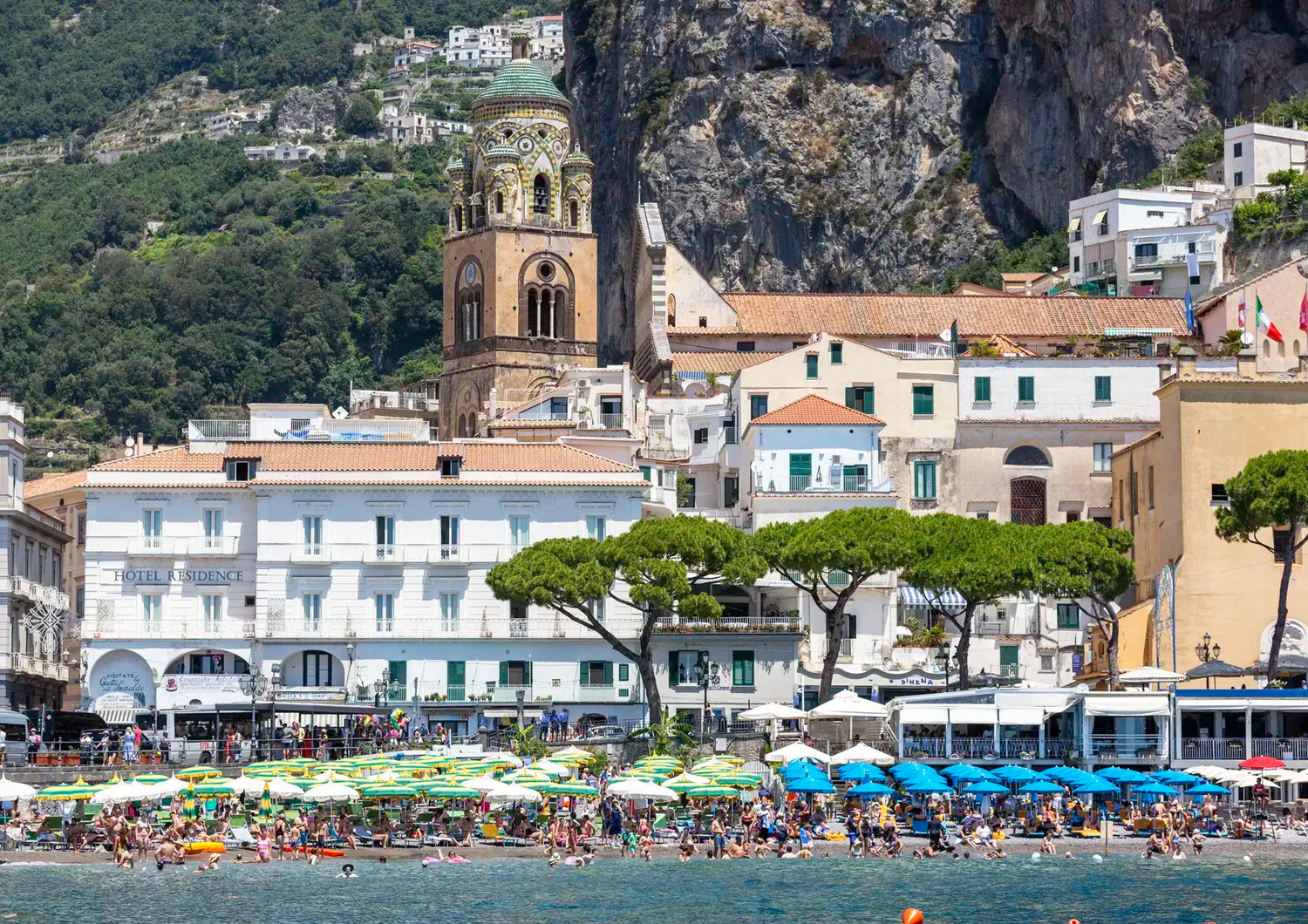 Scenic view of a coastal town with a church and people by the water