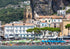 Scenic view of a coastal town with a church and people by the water