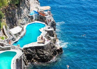 Two pools built into a rocky cliffside with ocean view