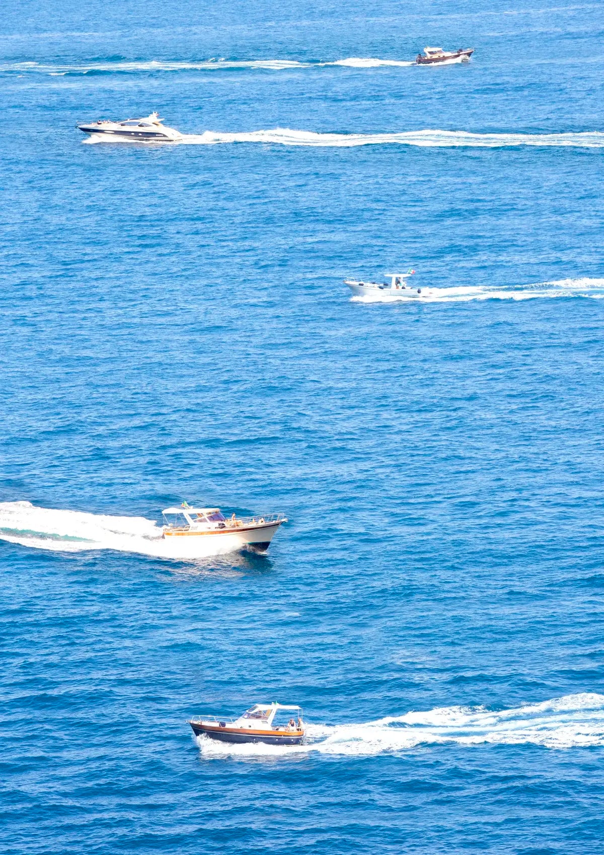 Multiple boats on a body of water with clear blue skies.