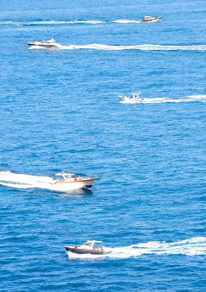 Multiple boats on a body of water with clear blue skies.
