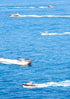 Multiple boats on a body of water with clear blue skies.