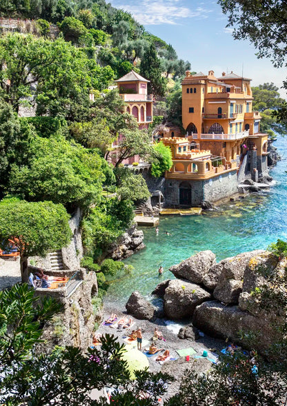 Luxurious waterfront villa in Portofino with gardens and a pool, surrounded by trees and rocks.