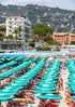 Beach scene with rows of green umbrellas and people under a cloudy sky.