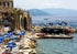 Coastal scene with stone building, umbrellas, and boats near water