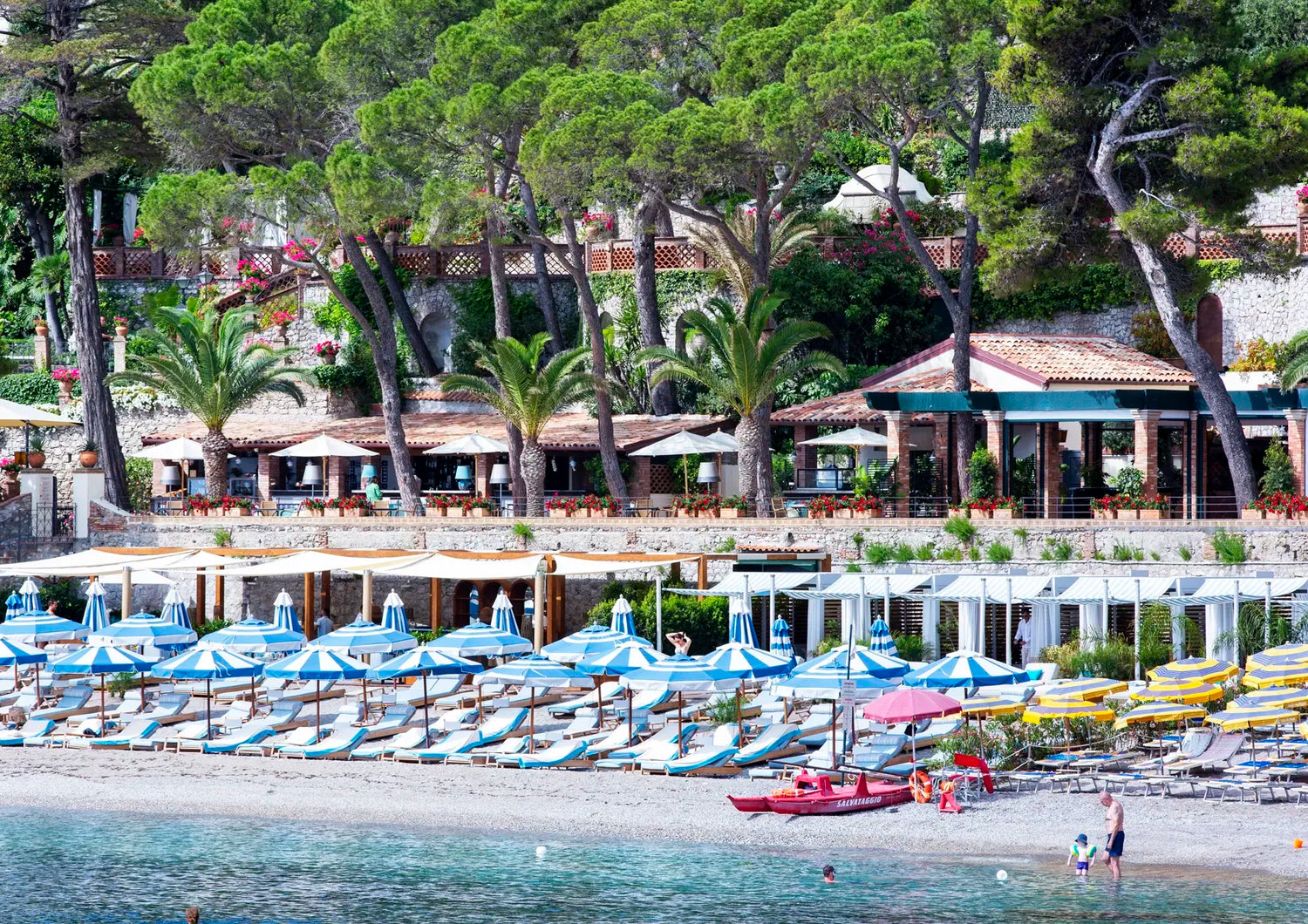 Beachside resort with umbrellas, lounge chairs, and a view of the water.