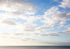 Blue sky with scattered clouds over a body of water