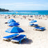 Beach scene at Bondi beach with blue umbrellas and lounge chairs on a sandy shore.