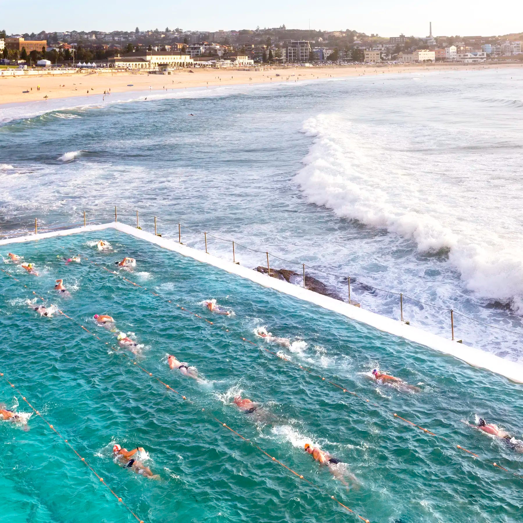 People swimming in a pool with ocean waves in the background