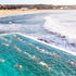 People swimming in a pool with ocean waves in the background