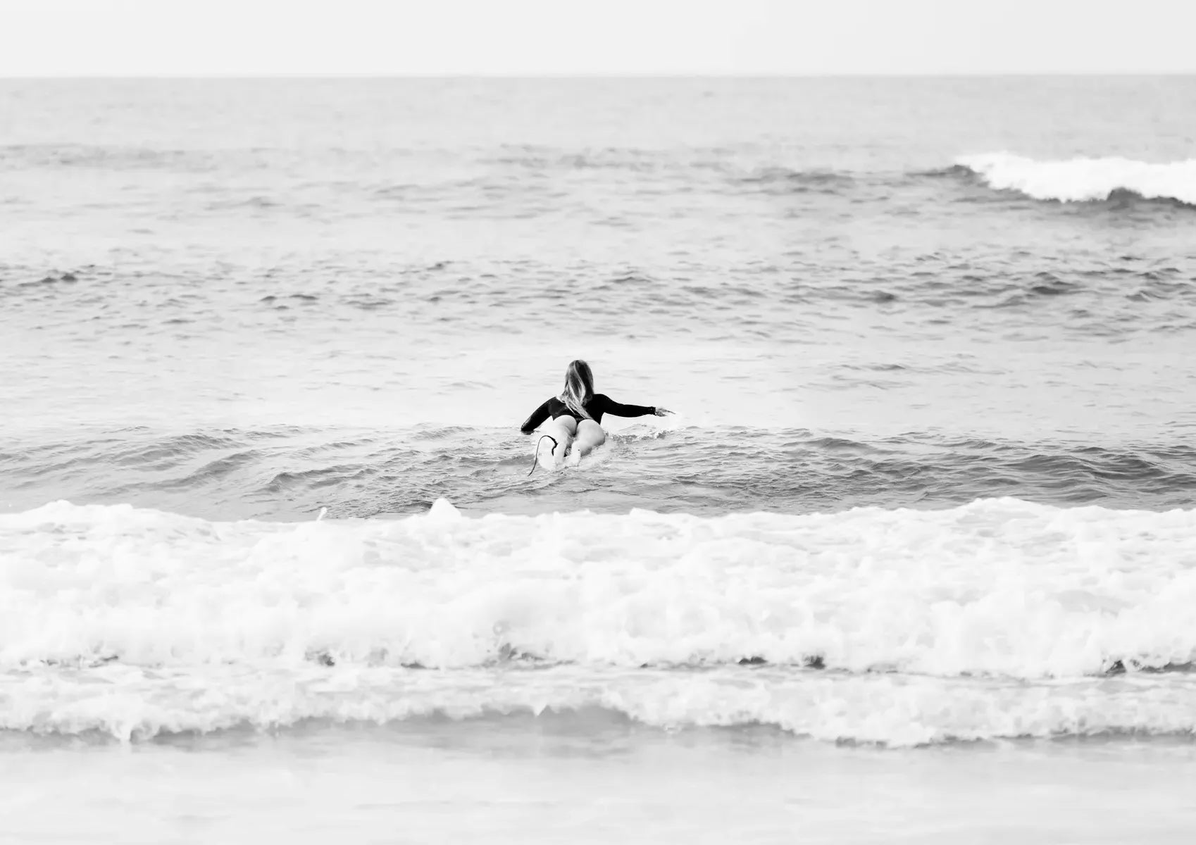 Female surfer paddling out to surf
