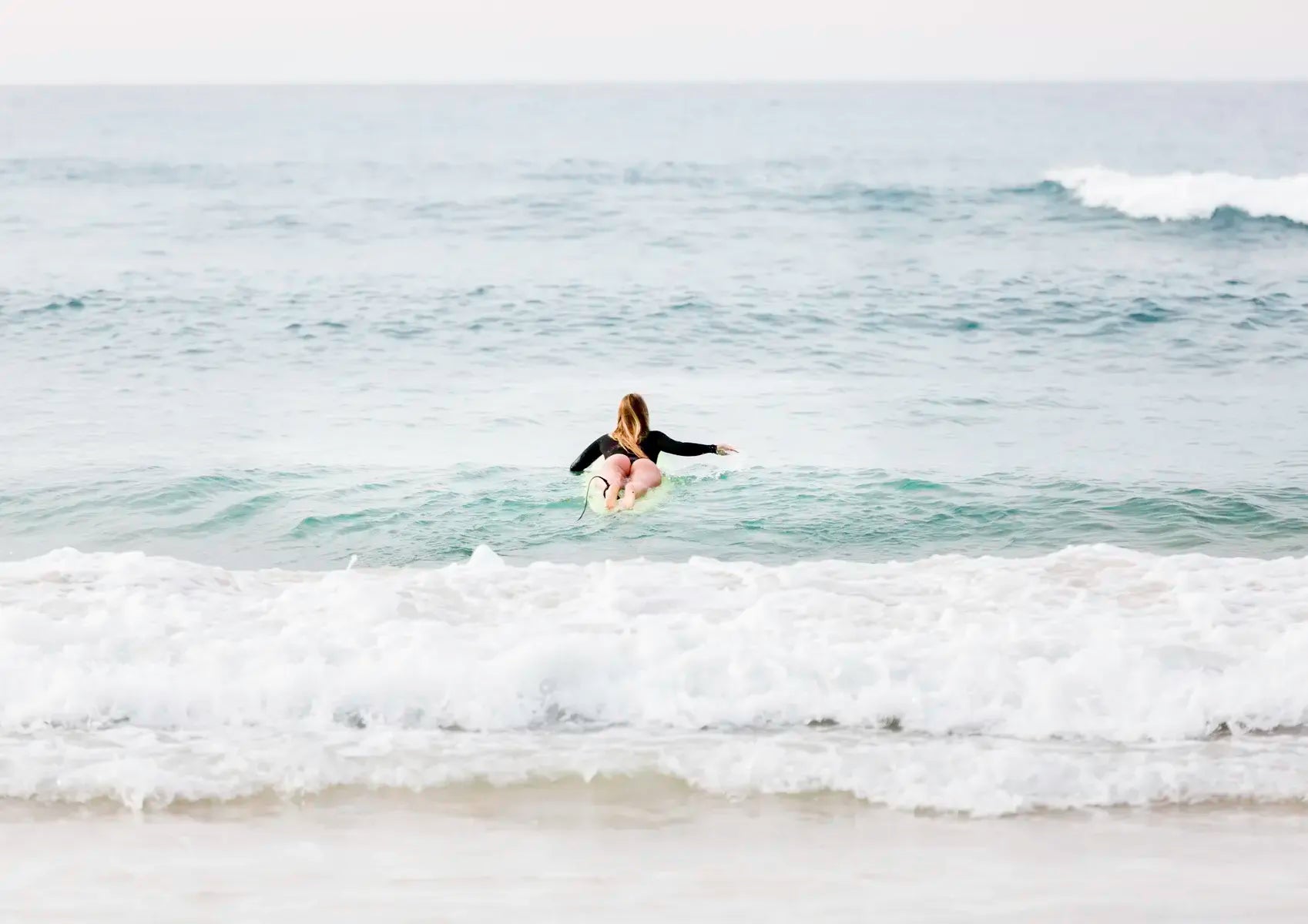 Female surfer paddling out to surf