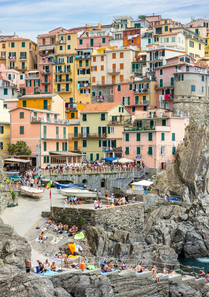 Colorful coastal hilltop town with people on the cliffs and in the water.