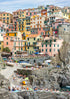 Colorful coastal hilltop town with people on the cliffs and in the water.