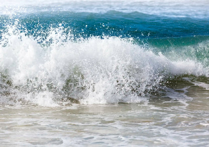 Powerful wave crashing onto a shore with white foam.