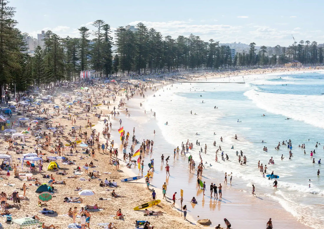 Busy beach with people and umbrellas on a sunny day.