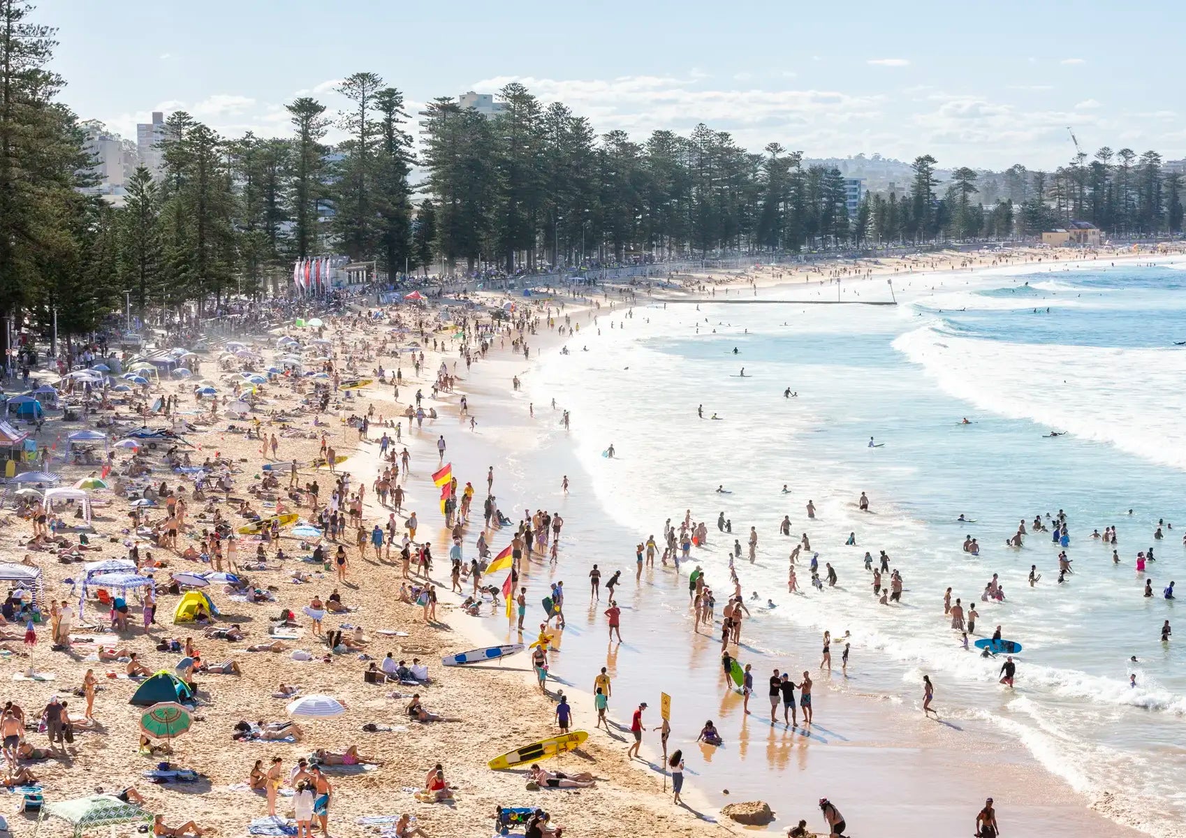 Busy beach with people and umbrellas on a sunny day.
