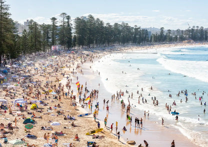 Busy beach with people and umbrellas on a sunny day.