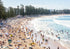 Busy beach with people and umbrellas on a sunny day.