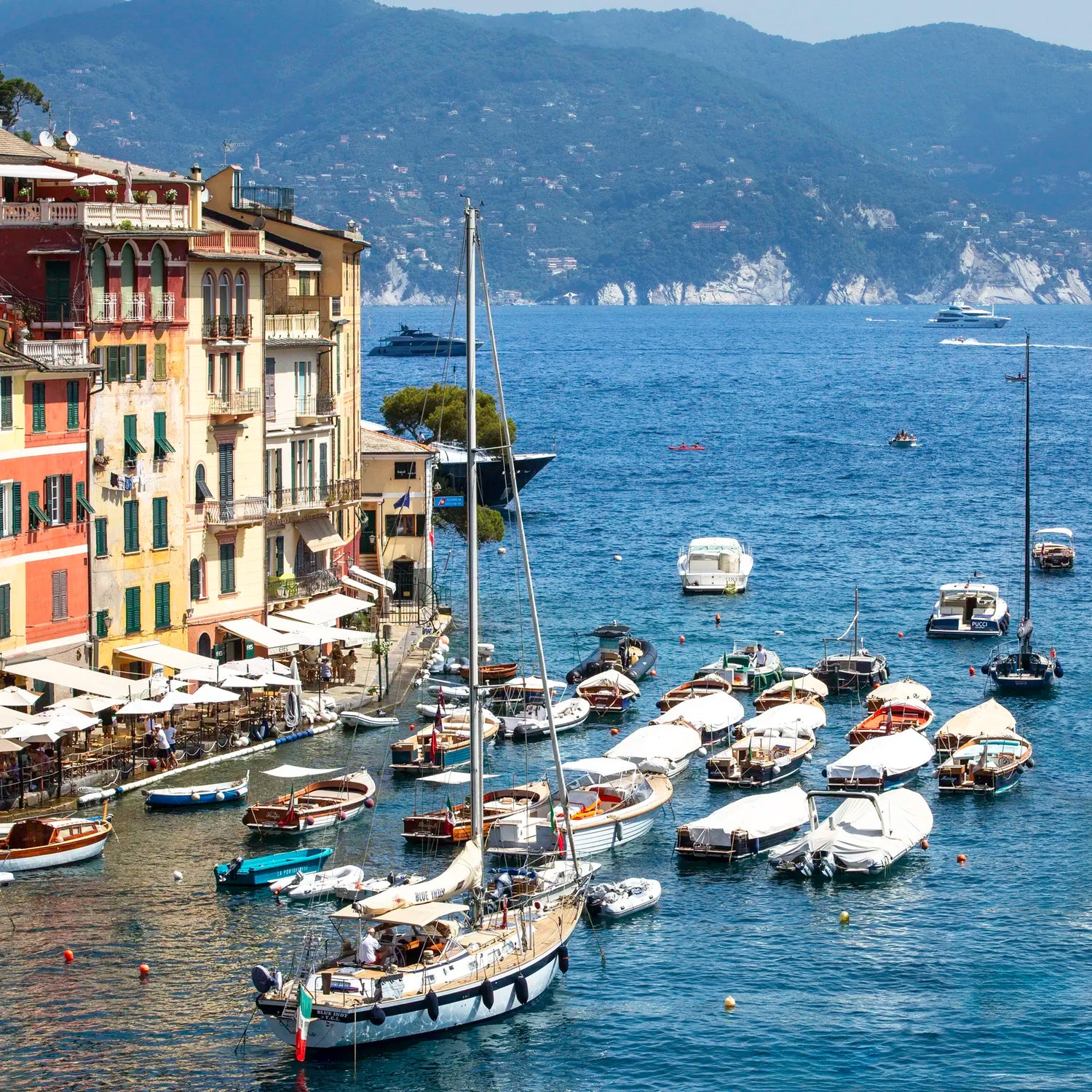 Harbor scene with boats and buildings by a mountainous coastline