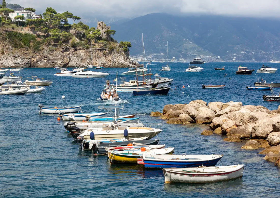 Boats docked in a harbor with rocky outcrops and mountains in the background
