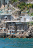 Staircase leading down to a cliffside with lounge chairs and umbrellas overlooking the ocean.