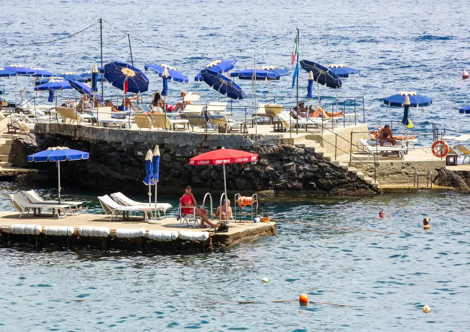 Rocky platform with lounge chairs and sun umbrellas next to the ocean