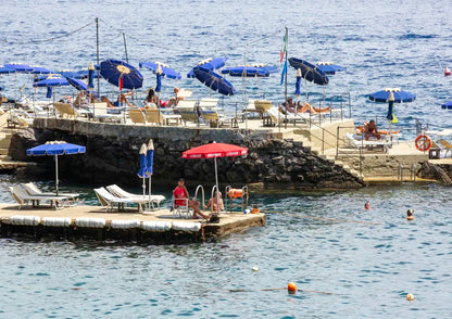 Rocky platform with lounge chairs and sun umbrellas next to the ocean