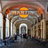 Neon Martini sign above a bustling cafe with people sitting at tables.
