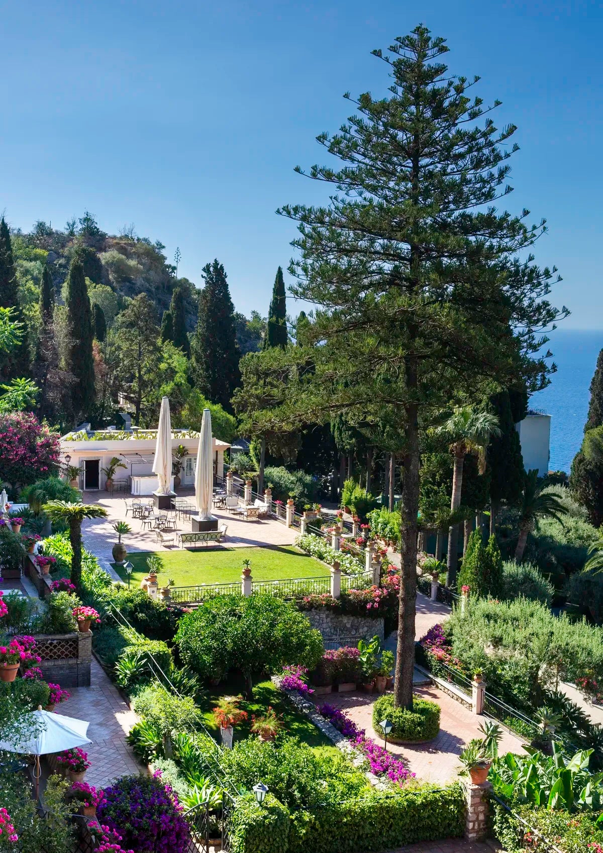 Gardens with classical architecture and trees under a clear blue sky
