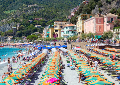 Beach scene with colorful umbrellas and buildings on a hillside.