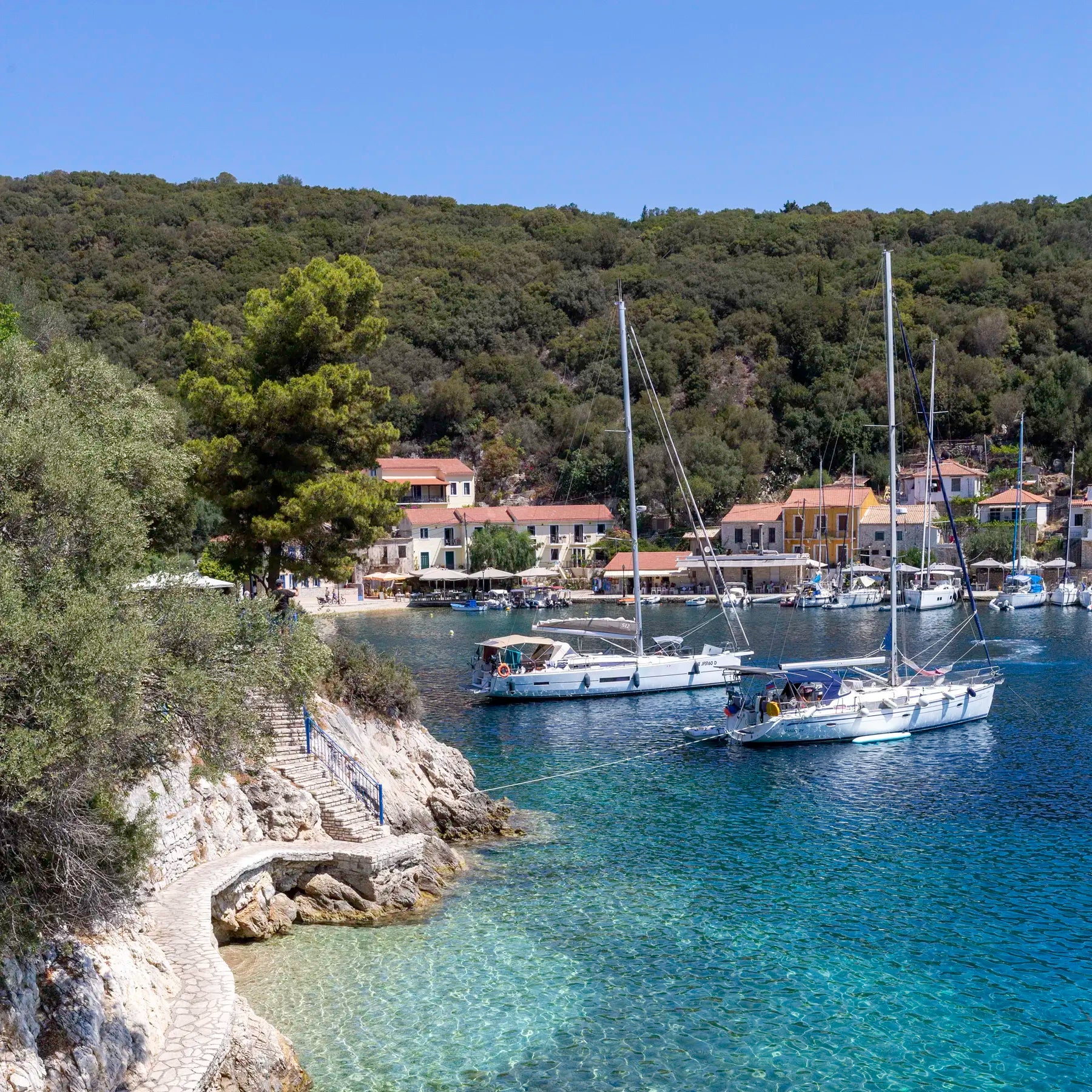 Kioni Harbour in Greece with sailboats and a coastal village surrounded by greenery