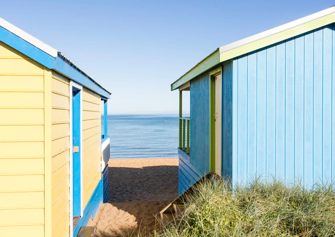Two colorful beach huts on a sandy area with ocean view