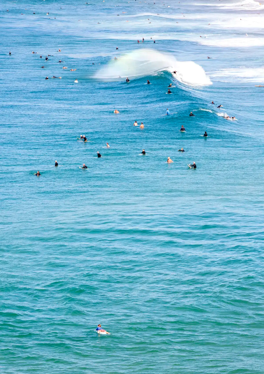 Surfers in the water with a large wave crashing behind them