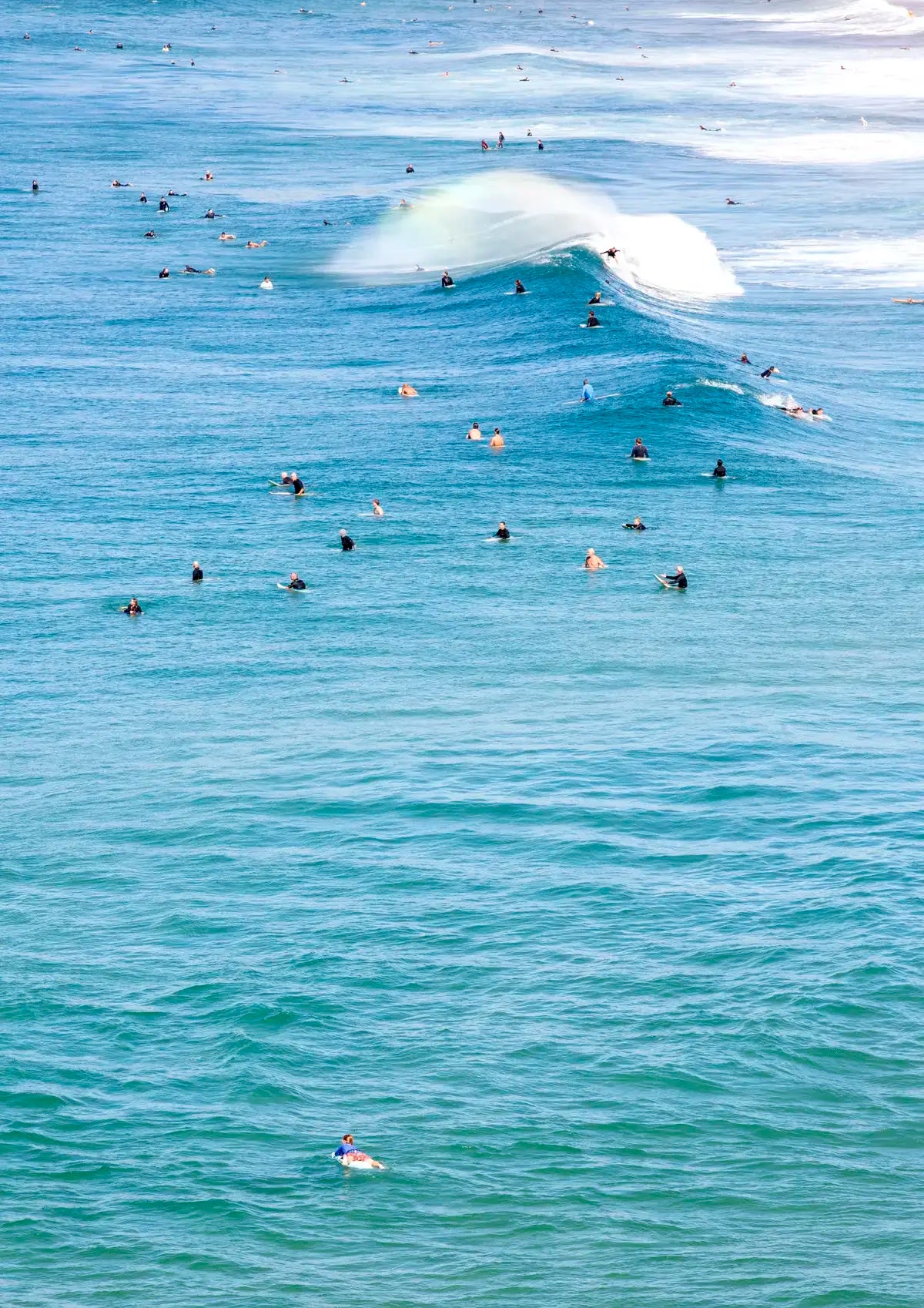 Surfers in the water with a large wave crashing behind them