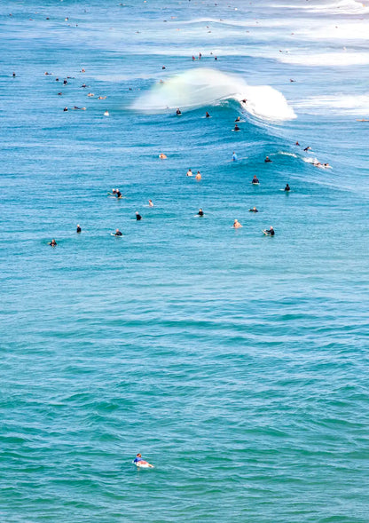 Surfers in the water with a large wave crashing behind them