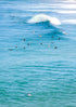 Surfers in the water with a large wave crashing behind them