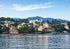 Cityscape with buildings along a waterfront, mountains in the background