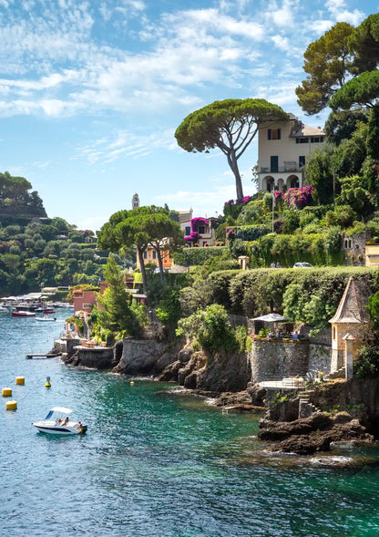 Coastal scene with houses, trees, and a boat on a clear day in Portofino.